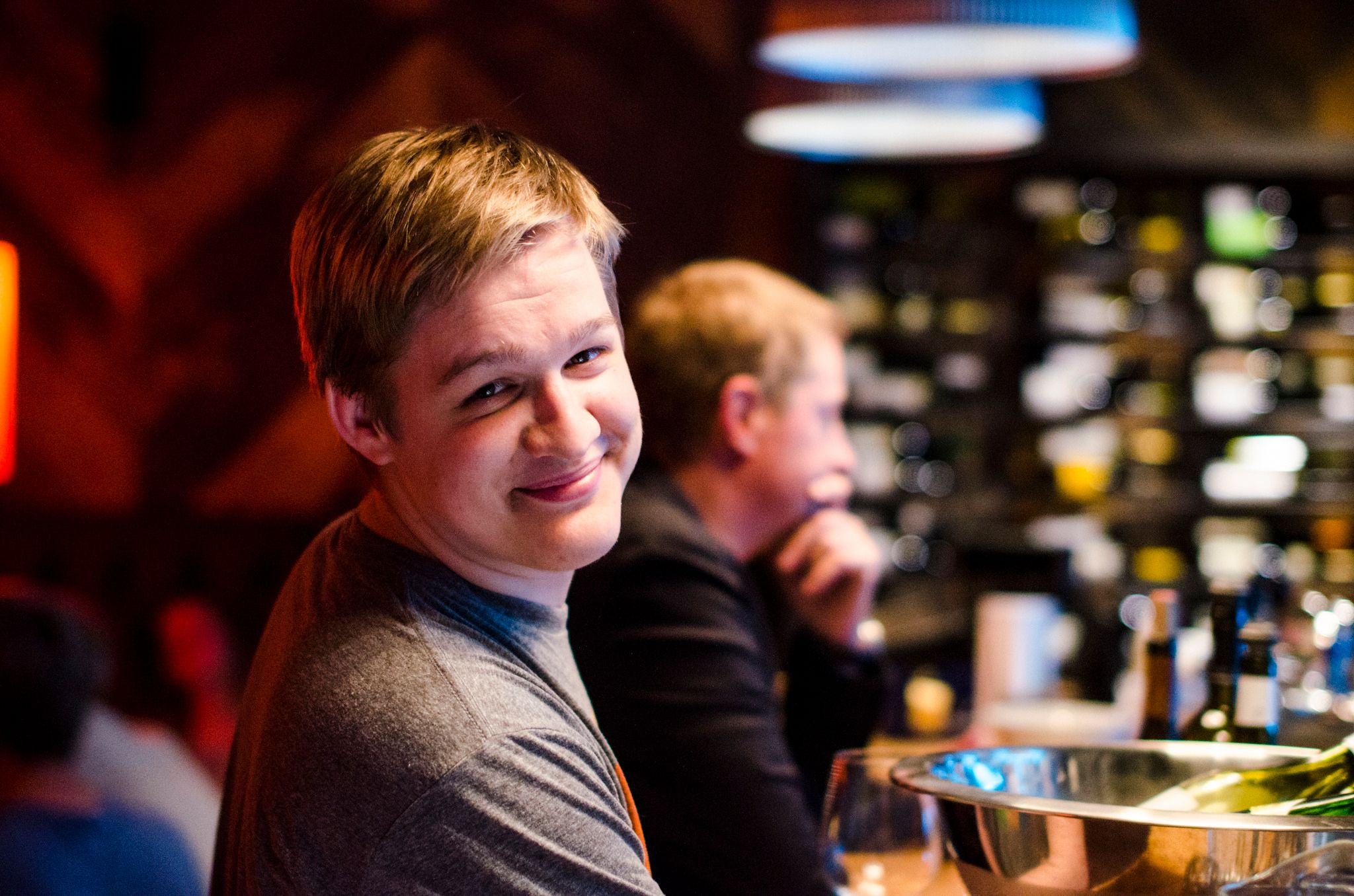 Mihkel smiling at the camera while waiting for service at a bar.